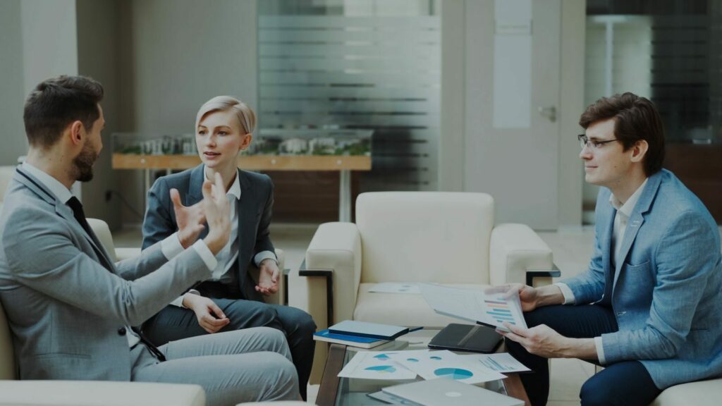 Three professionals engaged in a meeting with documents and charts in a modern office.